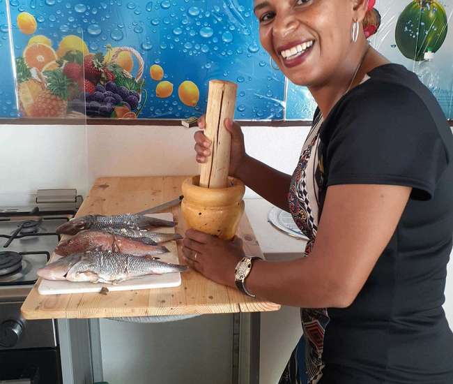 São Vicente - Frau bereitet in Küche Fische zum Kochen vor