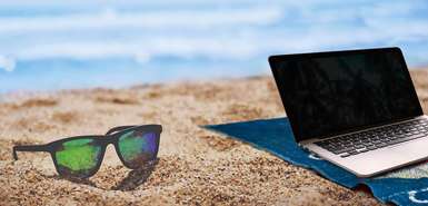 Laptop und Sonnenbrille am Strand