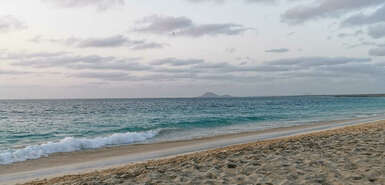 Wolken am leicht bunten Himmel, Meer und Strand