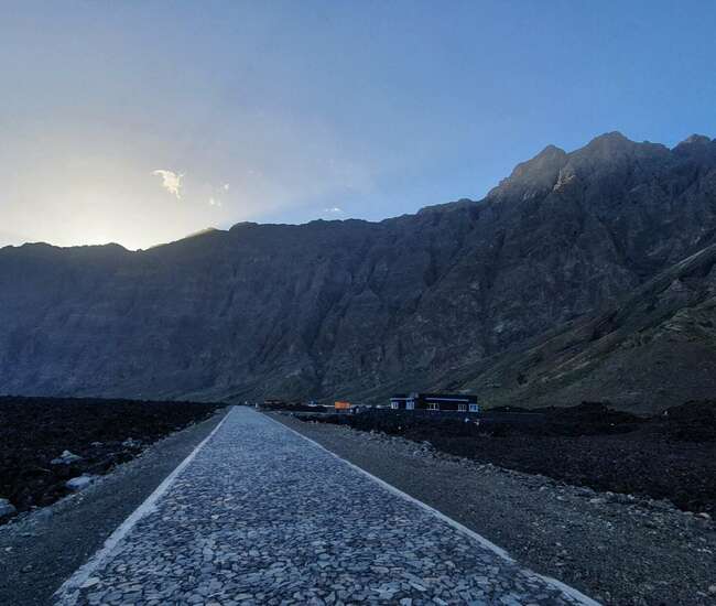 Lavastraße im Lavafeld, im Hintergrund geht die Sonne über der Bordeira auf