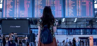 Frau vor Abflugtafeln am Flughafen